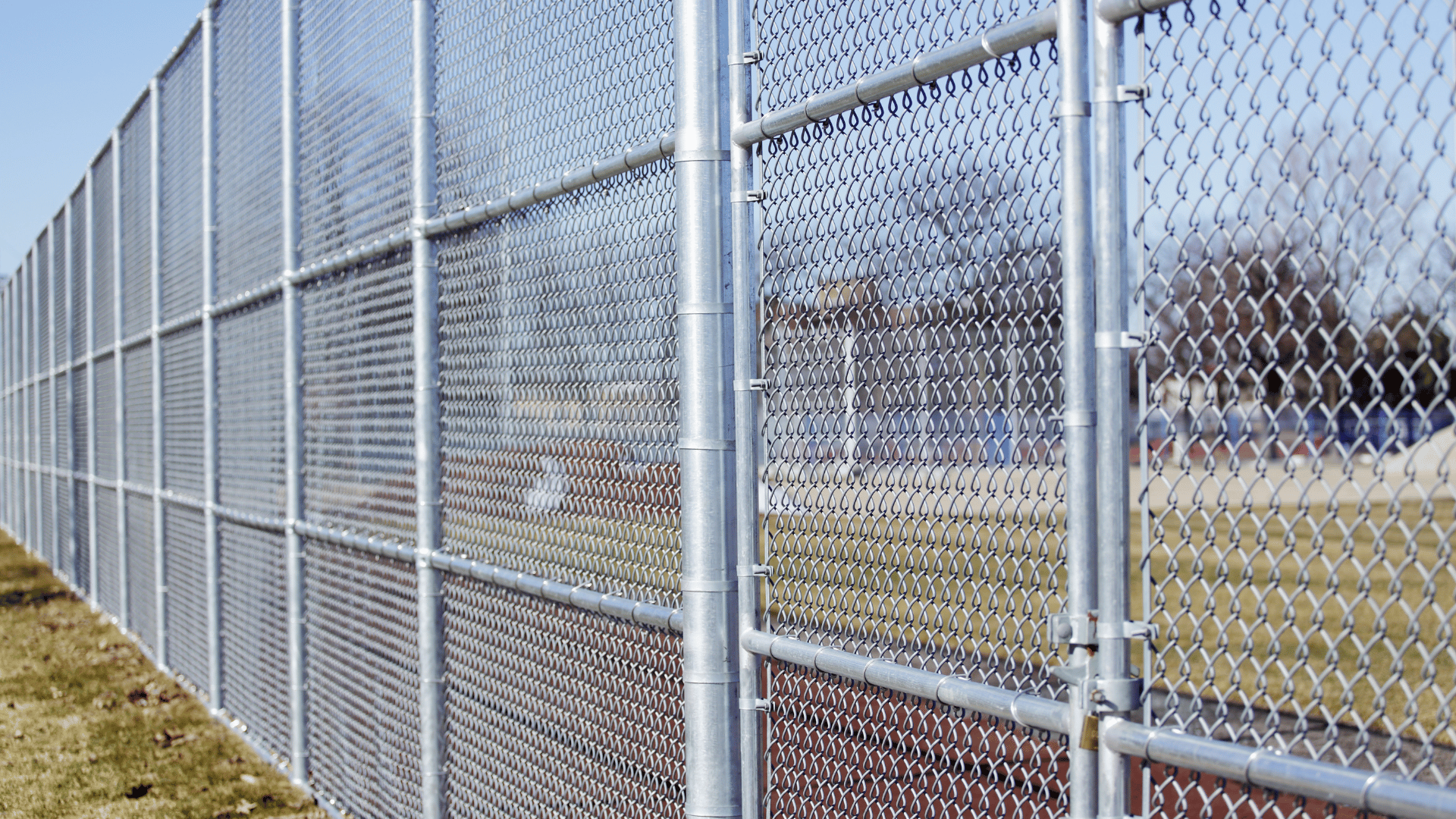 Chain link fence surrounding a field with a gate.