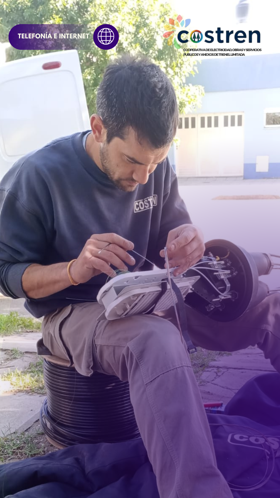 Hombre trabajando con cables de fibra óptica, sentado al aire libre cerca de una camioneta, con el logo