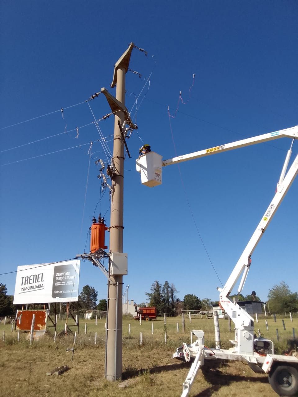 Los trabajadores de servicios públicos en un elevador reparan cables eléctricos en un poste de hormigón