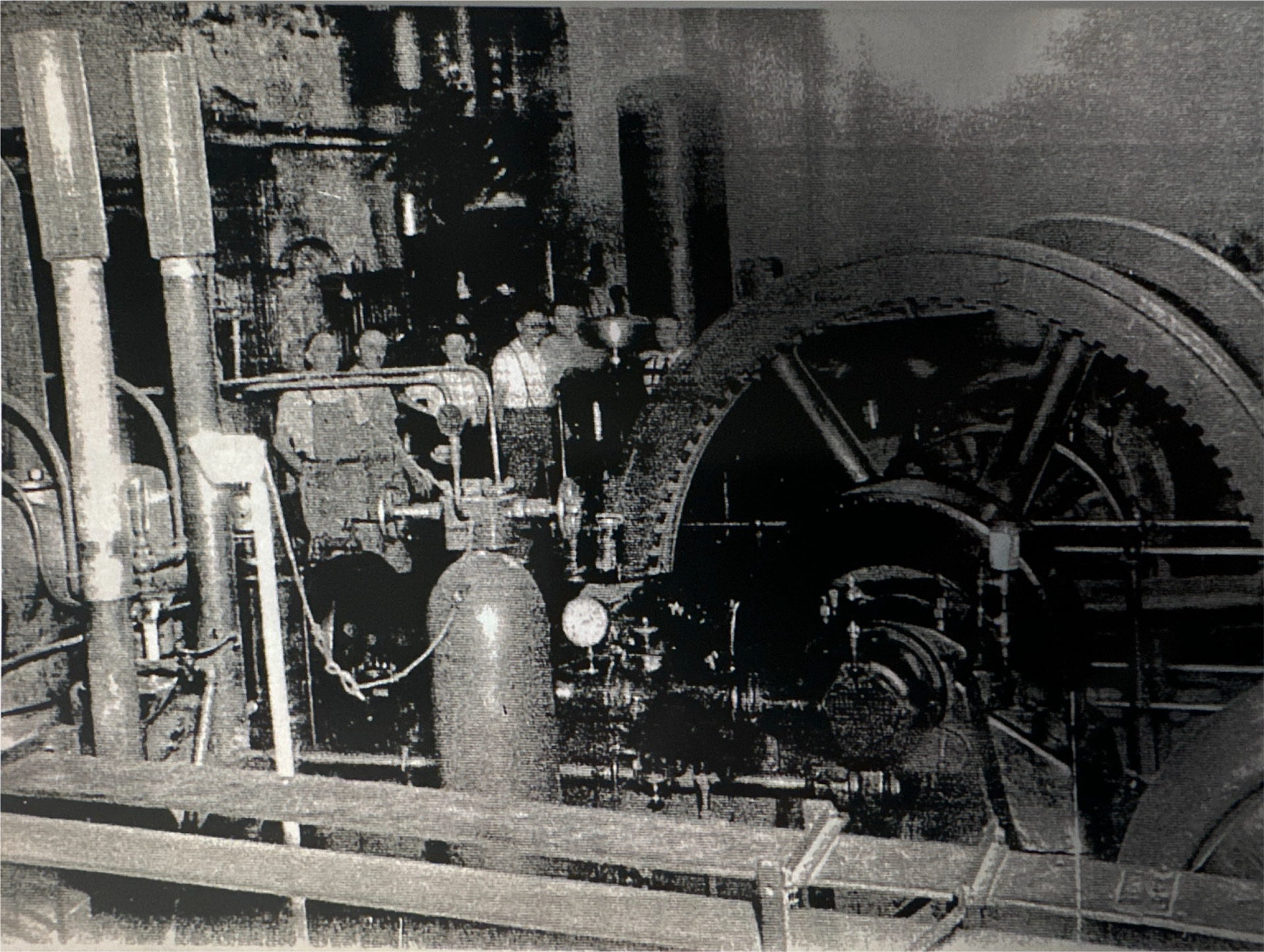 Los hombres se reúnen alrededor de una maquinaria industrial, posiblemente un montacargas de mina.