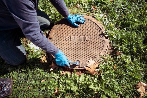 Technician performing septic system inspections in Concord, NC, opening septic tank for routine main