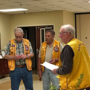 Three men wearing yellow vests are standing in a room.