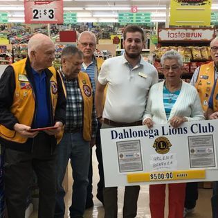 A group of people are standing in a store holding a sign that says ' dahlonga lions club ' on it.