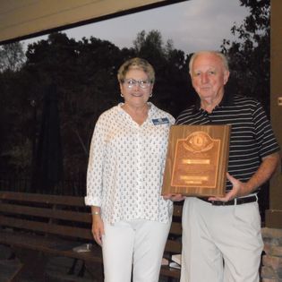 A man and a woman holding a wooden plaque