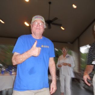 A man in a blue shirt is giving a thumbs up