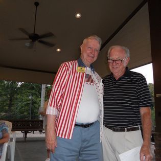Two men are posing for a picture and one is wearing an american flag shirt