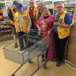 A group of people standing around a shopping cart in a store