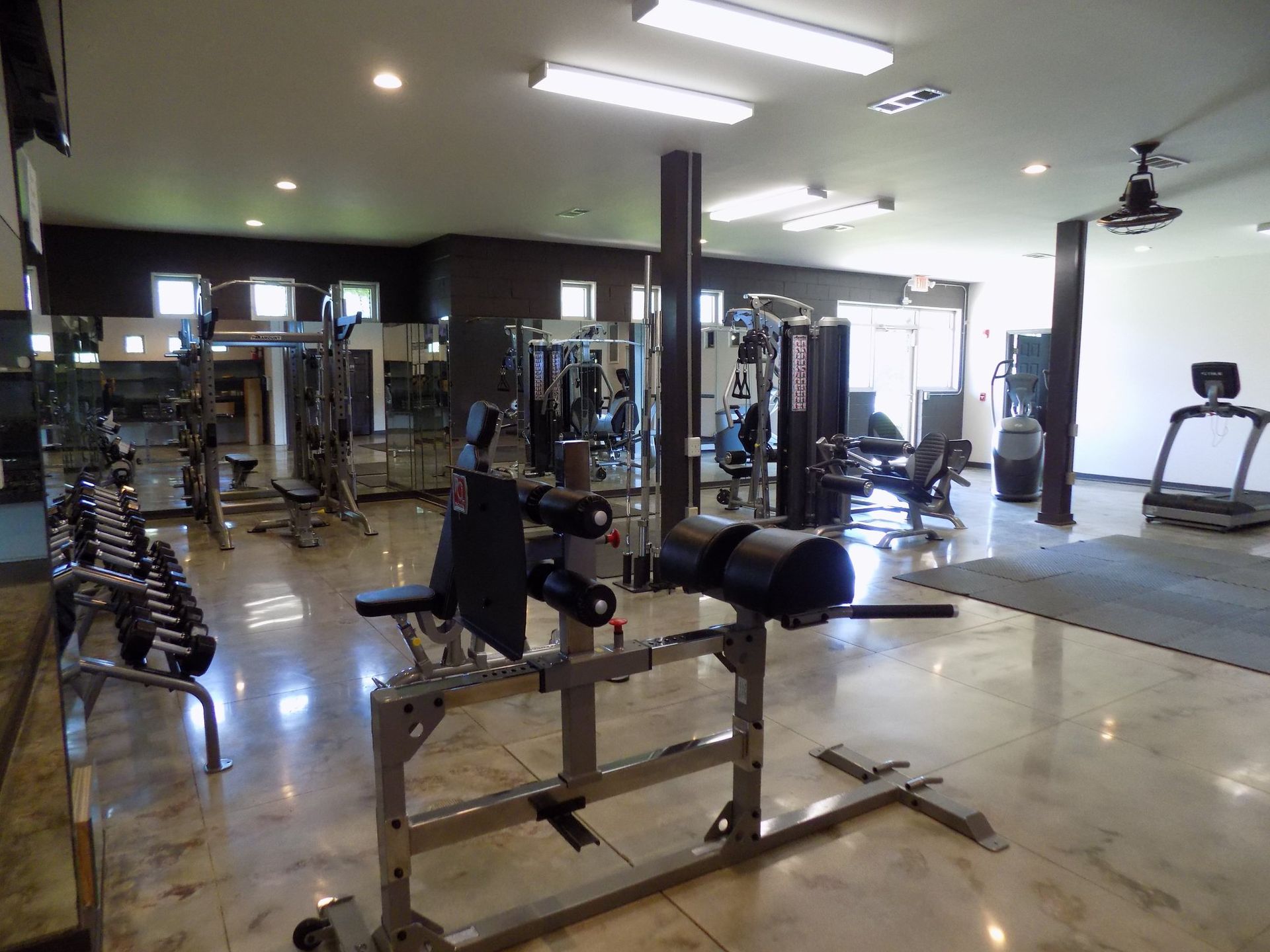 A large gym with lots of exercise equipment and a treadmill .