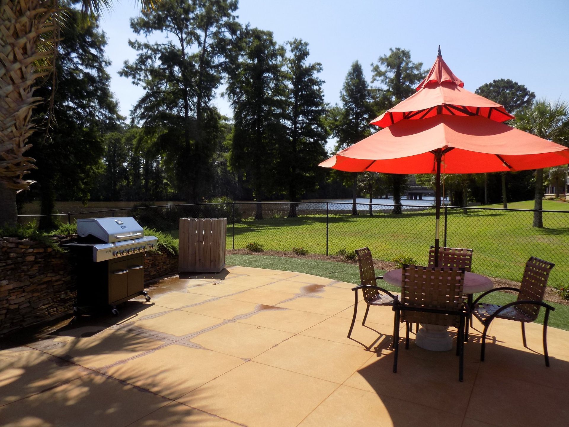A patio with a table and chairs and an orange umbrella