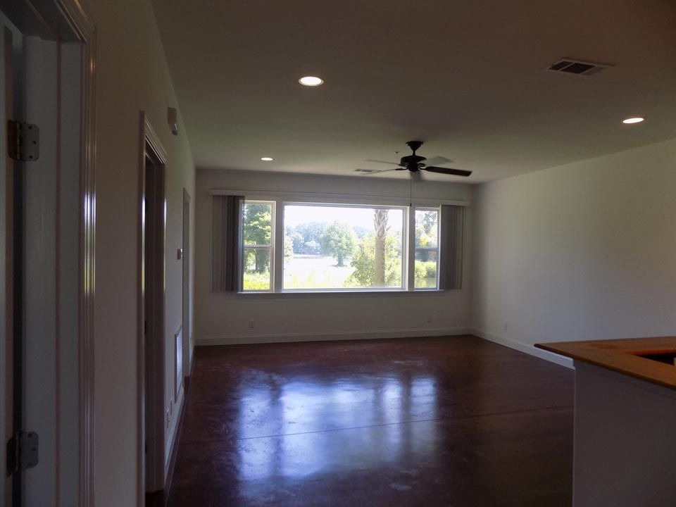 An empty living room with a ceiling fan and a large window .