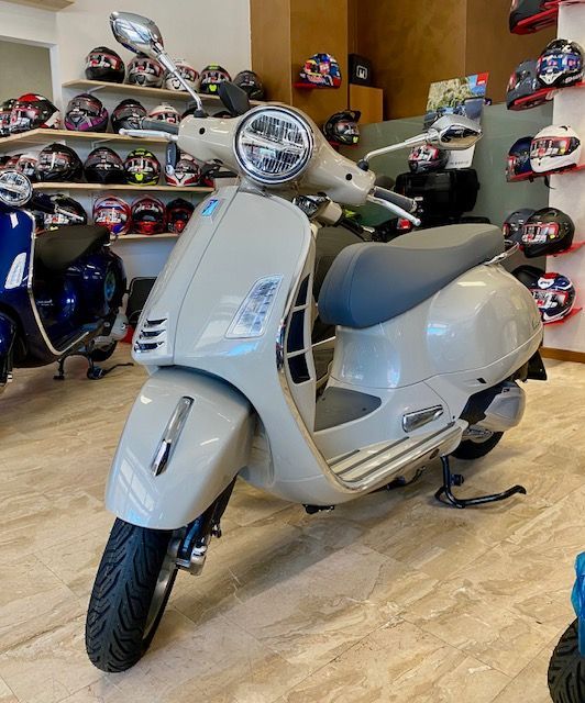 Una motocicletta bianca e nera è parcheggiata su una superficie bianca.