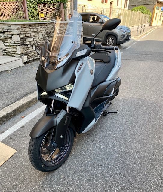 Una motocicletta bianca e nera è parcheggiata su una superficie bianca.