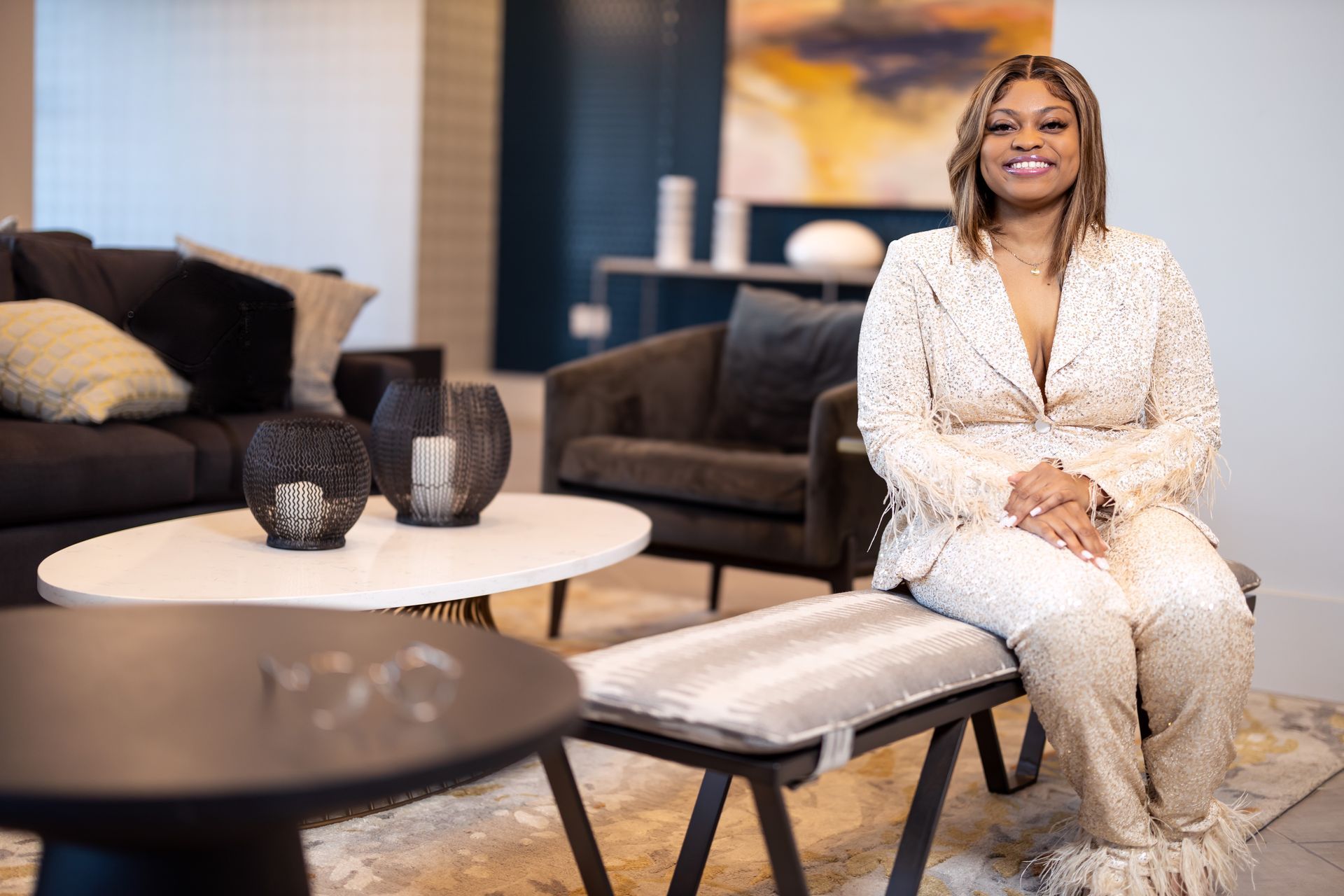 Woman with dark hair in patterned shirt, hand to chin, posing against white background.