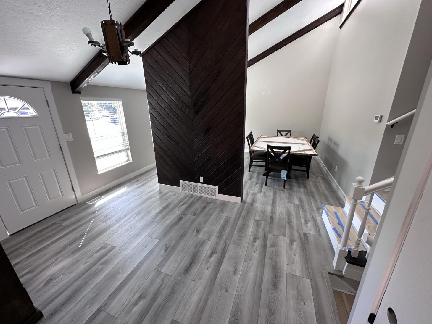 a living room with a dining room table and chairs and stairs .