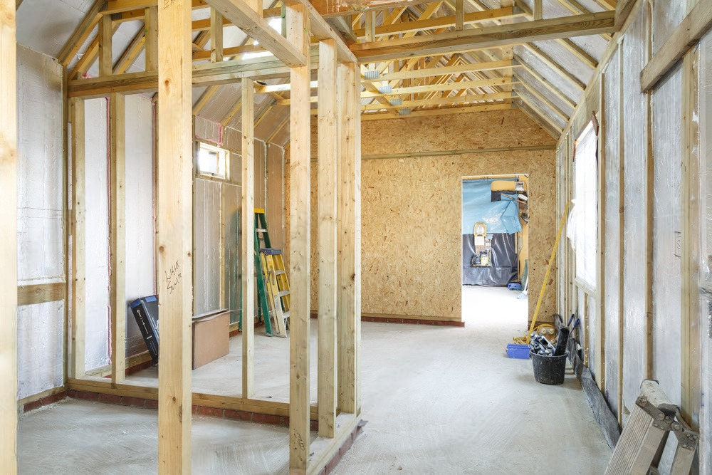 a room under construction with wooden beams and a ladder .