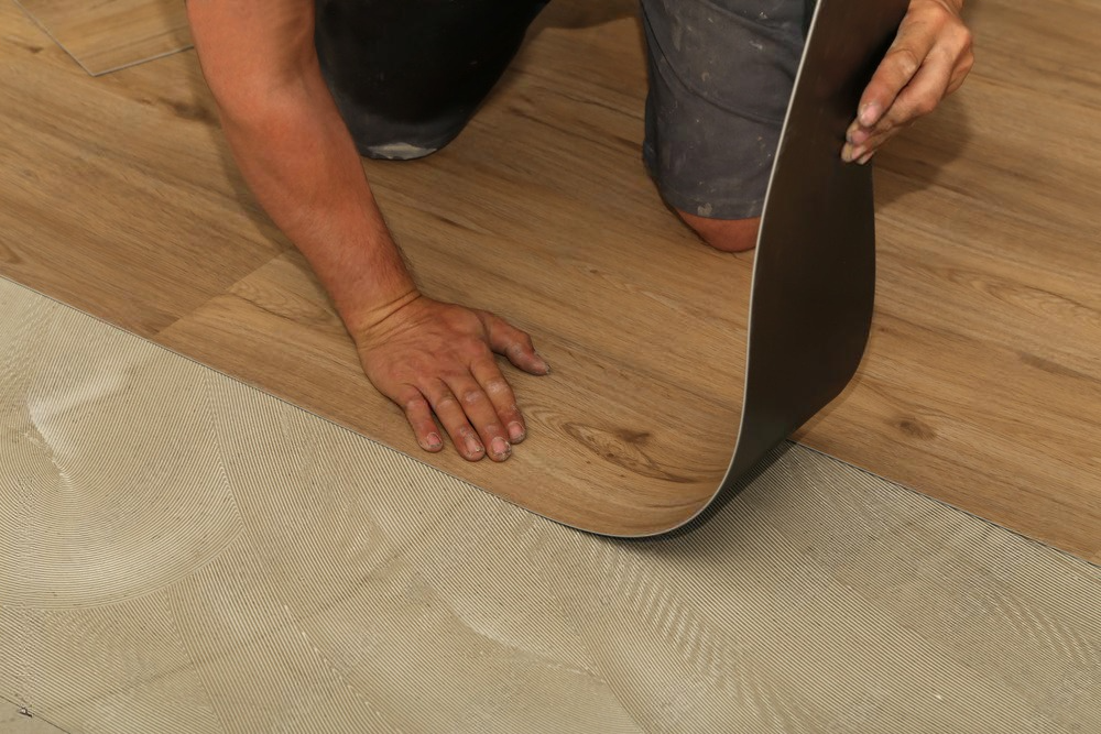 a person is laying a piece of vinyl flooring on the floor .