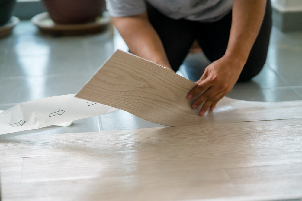 a person is laying a piece of wood on the floor .