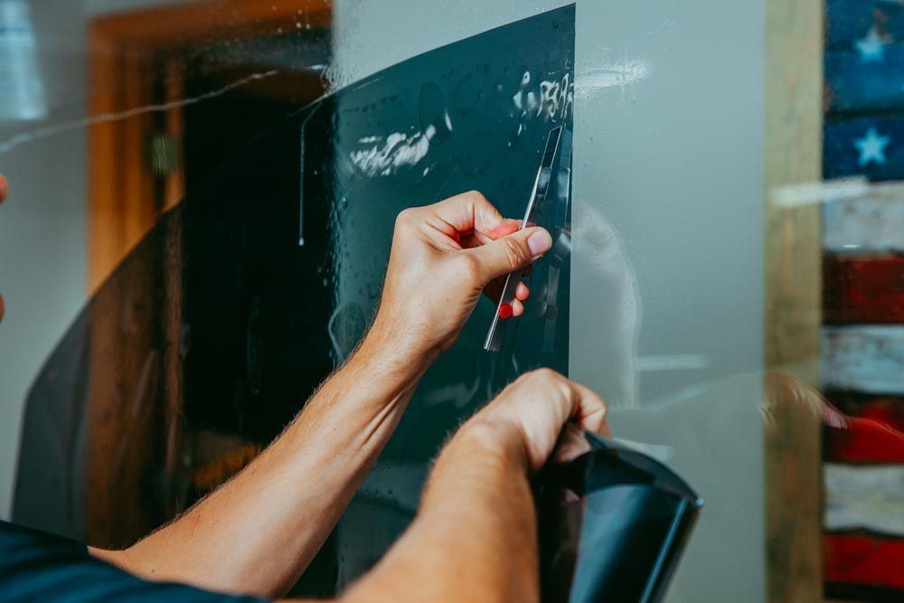 Hands writing on a glass board with a red marker in front of a dark screen and U.S. flag reflection