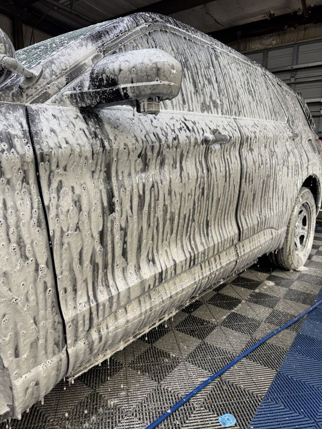 A person is washing a car wheel with foam