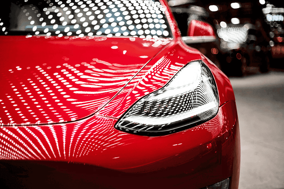 Close-up of a red sports car front headlight with glossy reflections