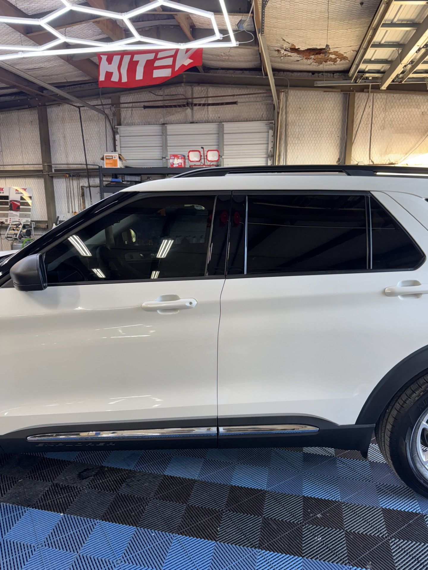 White SUV parked in an auto shop garage with a “MITER” sign overhead