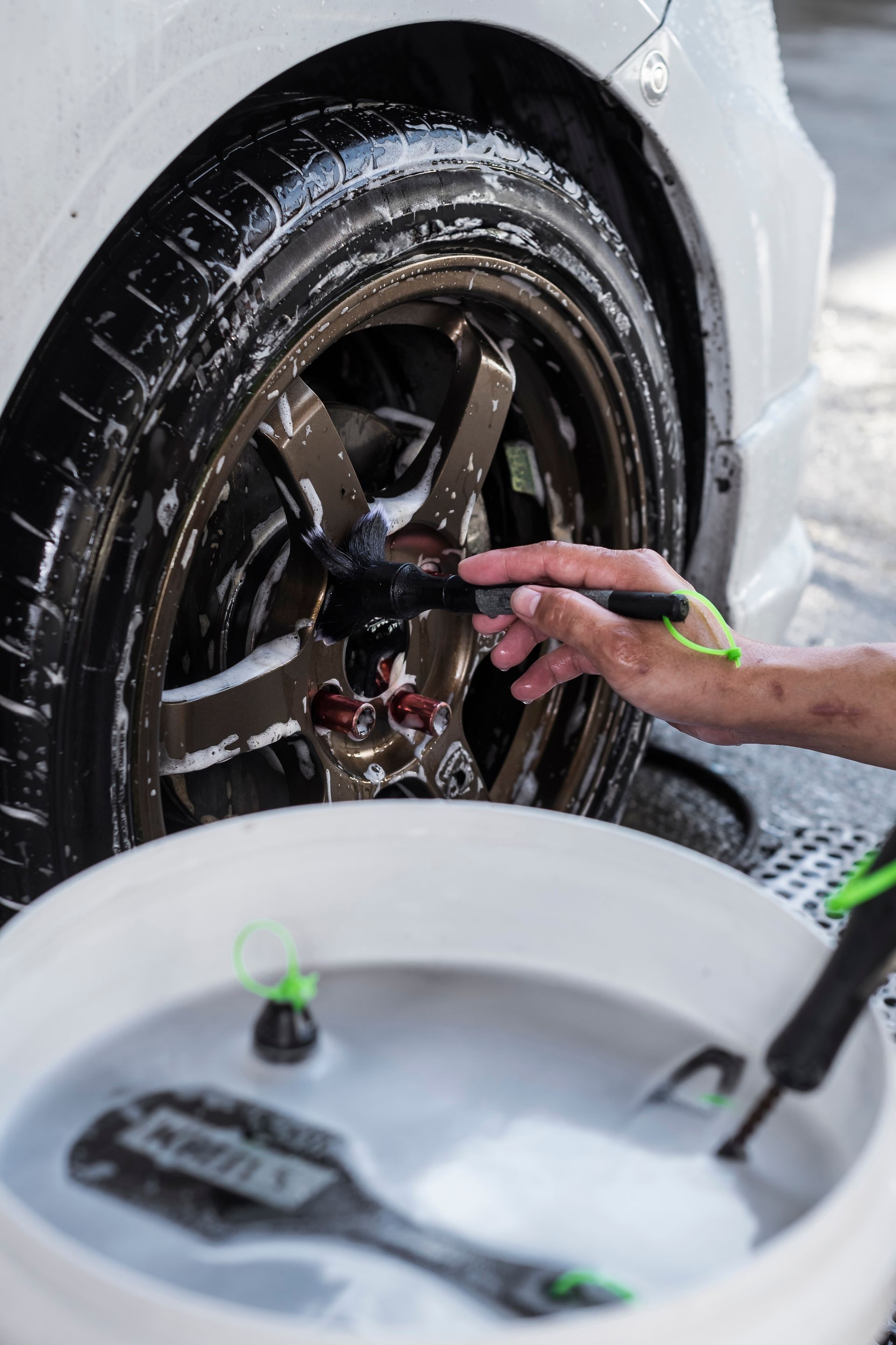 A person wearing black gloves is polishing a black car