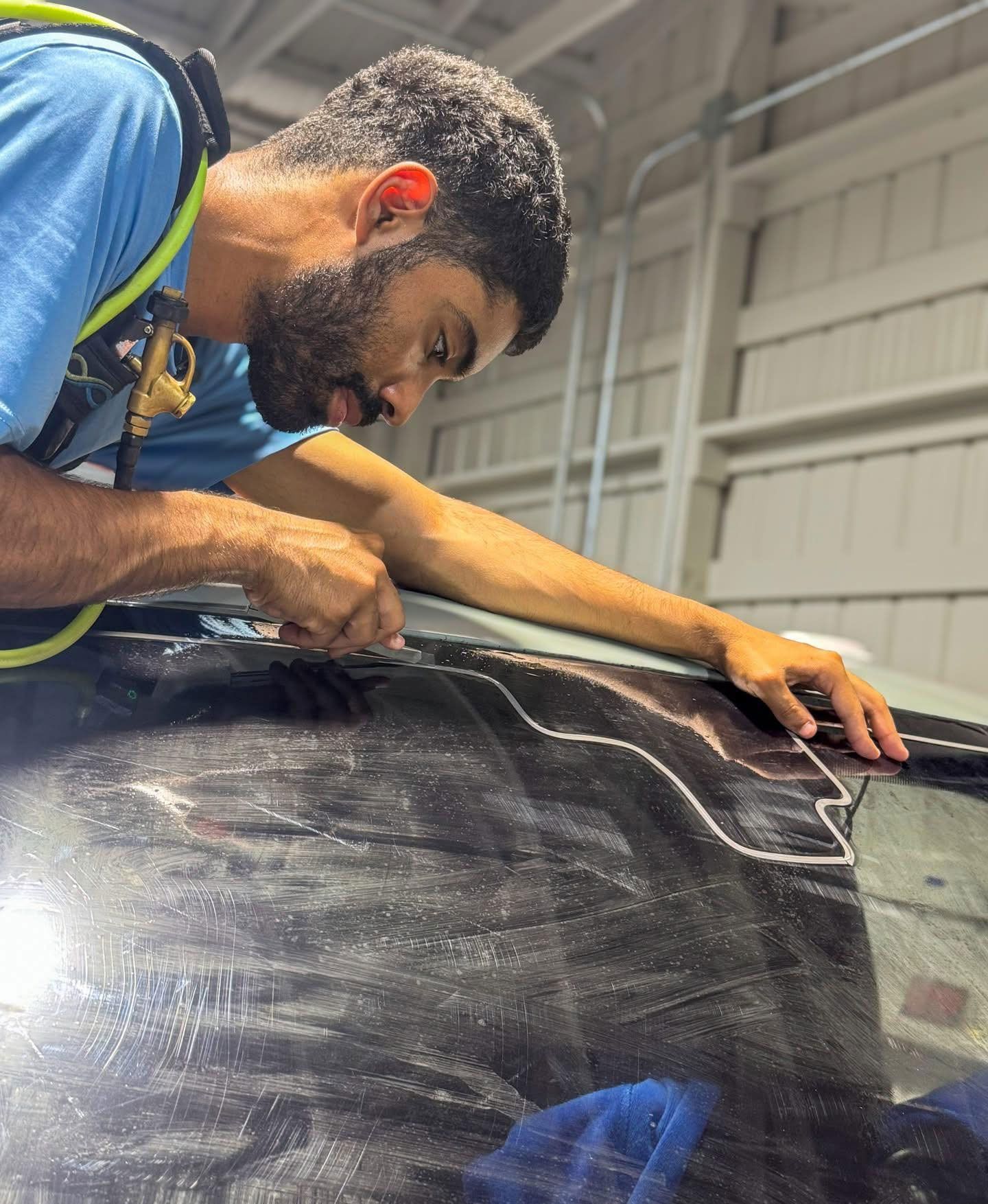 A person wearing black gloves is polishing the hood of a red car.