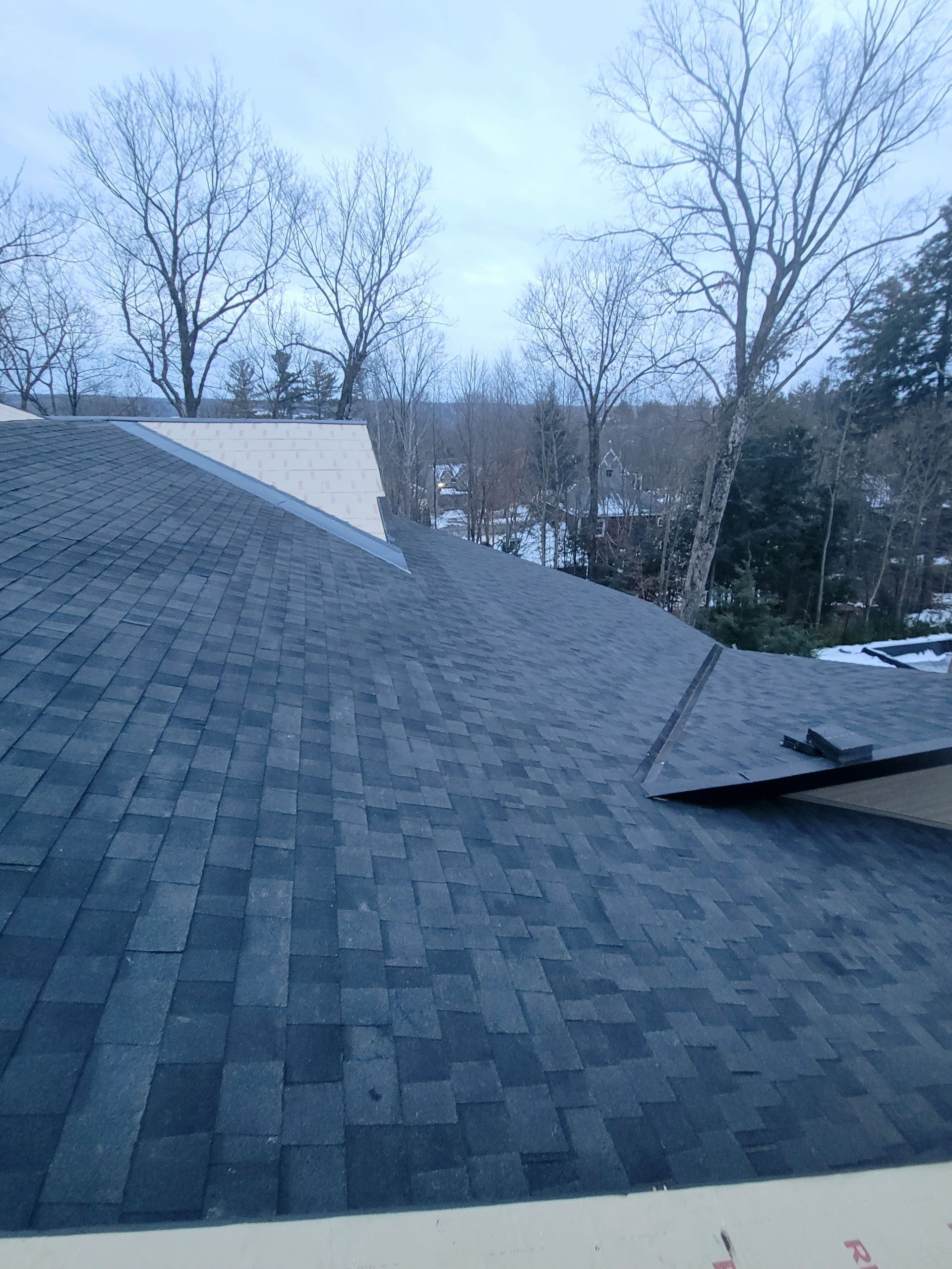 Un toit avec beaucoup de bardeaux et des arbres en arrière-plan.