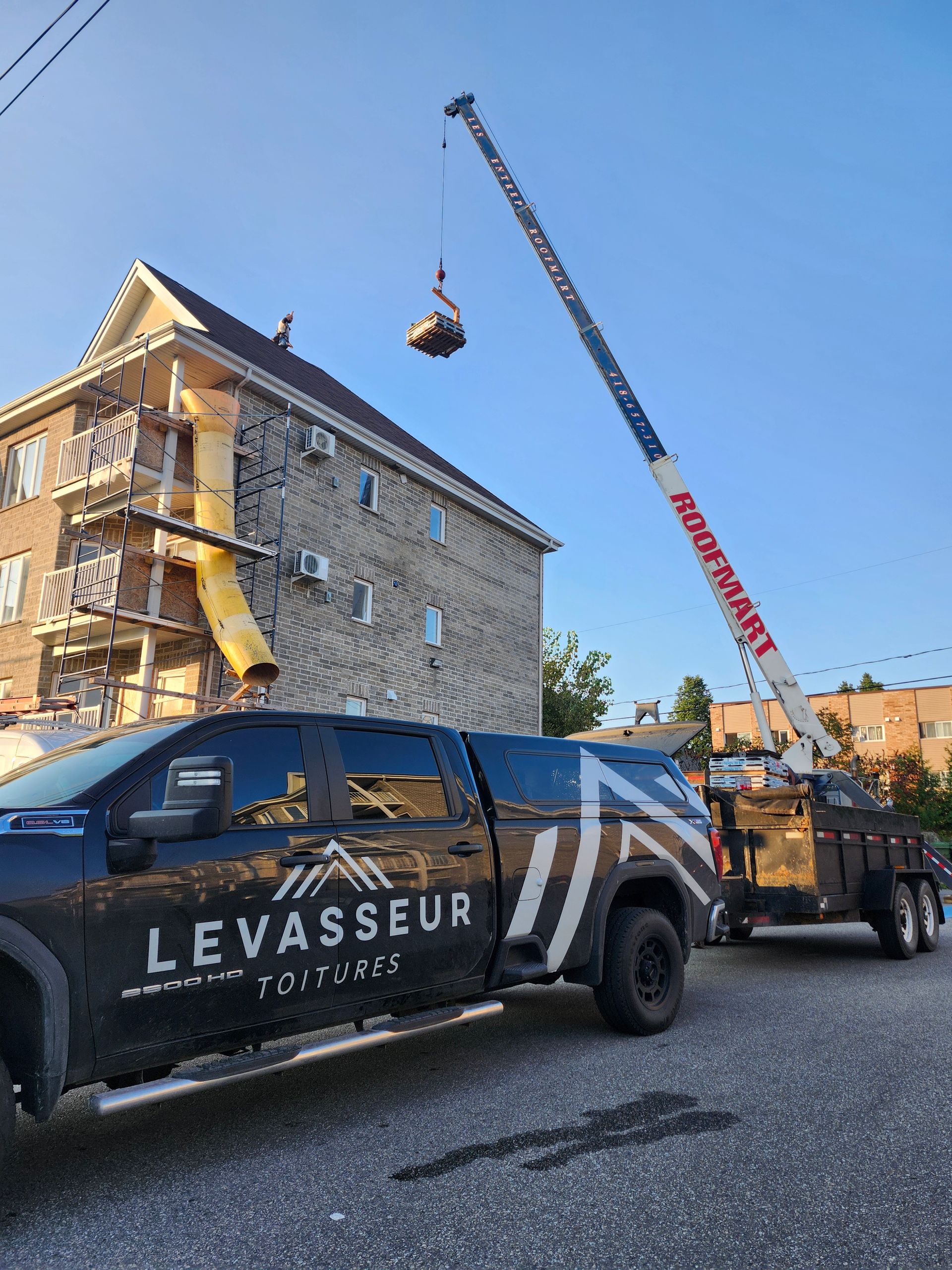 Un camion avec une grue attachée est garé devant un bâtiment.