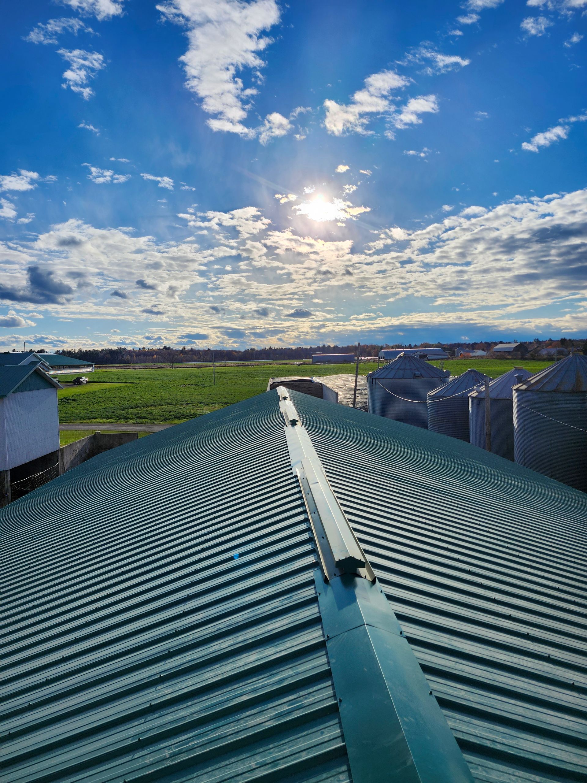 Le soleil brille à travers les nuages ​​au-dessus du toit d'un bâtiment.