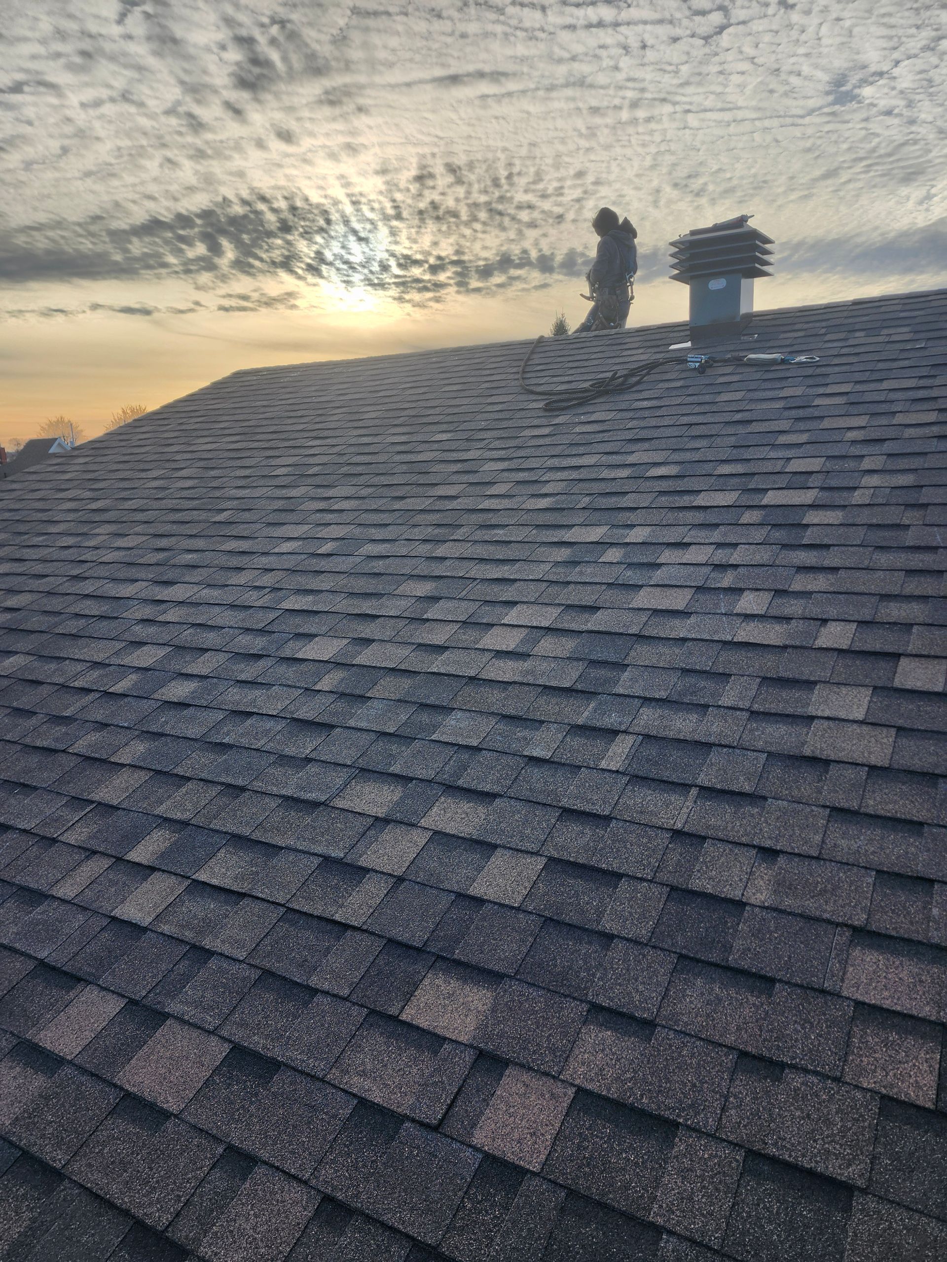 Un homme se tient au sommet d'un toit avec une cheminée.