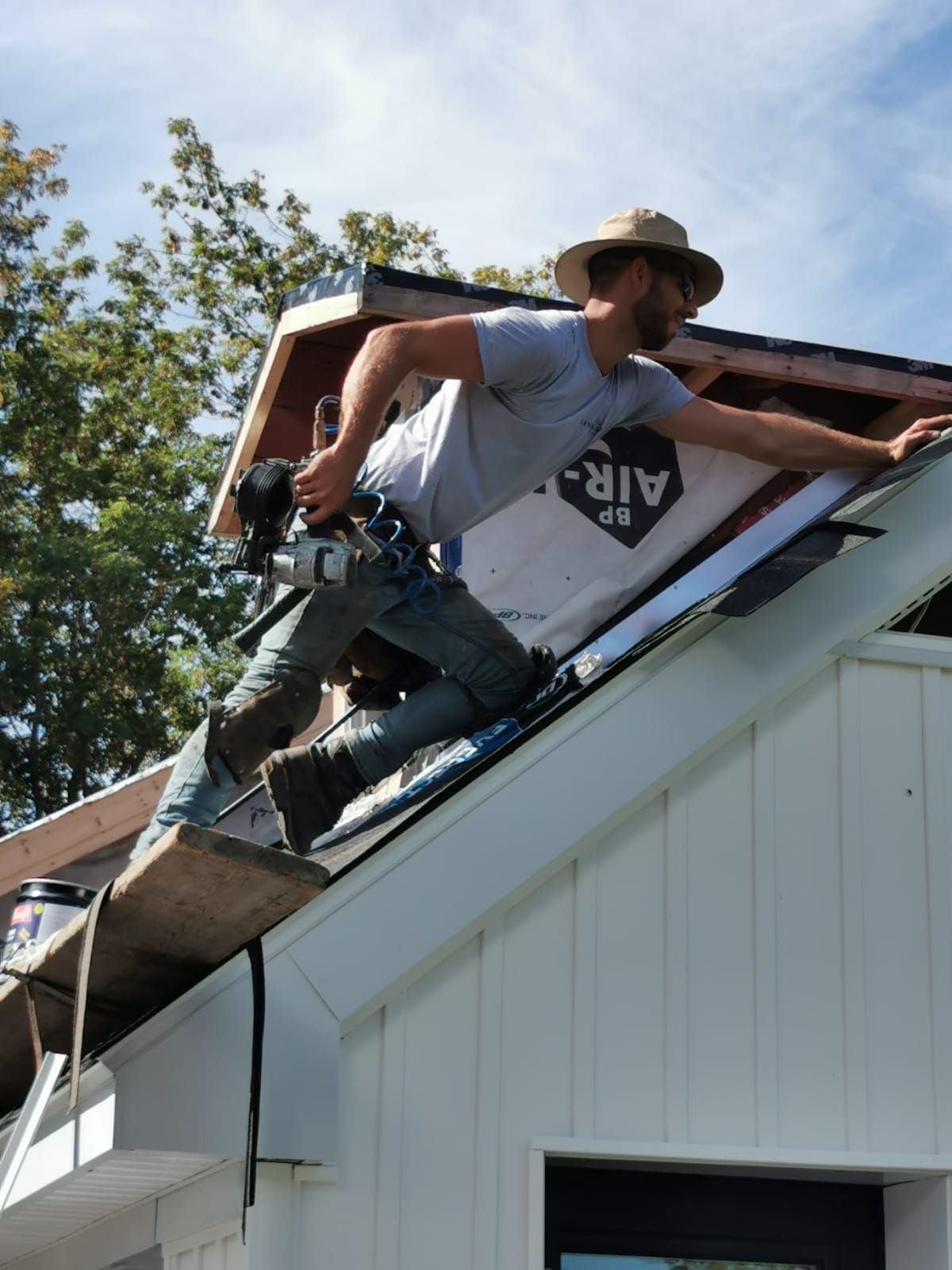 Un homme portant un chapeau travaille sur le toit d'une maison