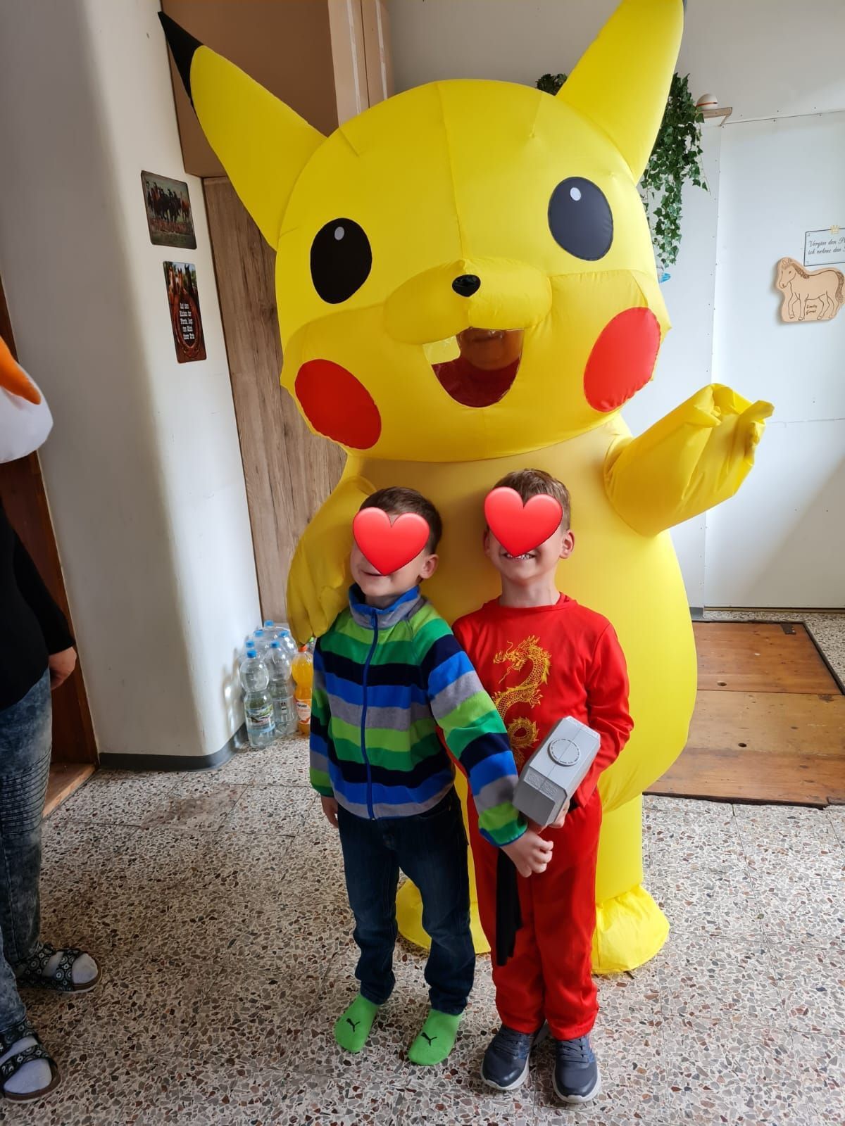 Zwei Kinder stehen neben einem aufblasbaren Pikachu-Kostüm.