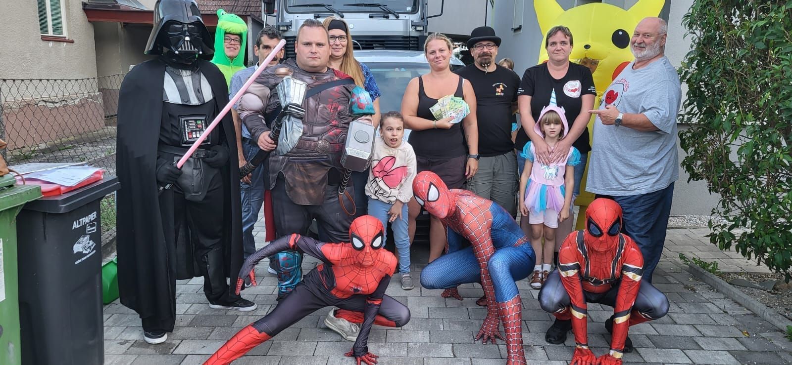 Eine Gruppe von Menschen in Superheldenkostümen und mit Schützling posiert für ein Foto.