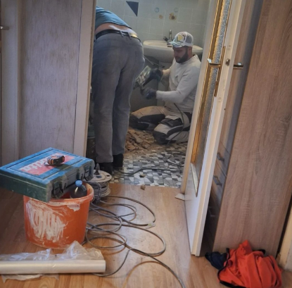 Ein Mann arbeitet in einem Badezimmer mit einem Eimer Farbe