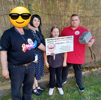 Eine Gruppe von Menschen, die nebeneinander stehen bei einer Spendenscheckübergabe.