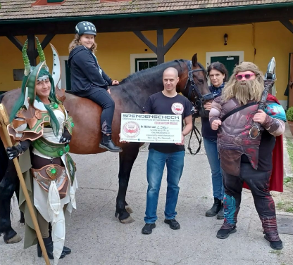 Eine Gruppe von Menschen steht um ein Pferd herum und hält eine Urkunde