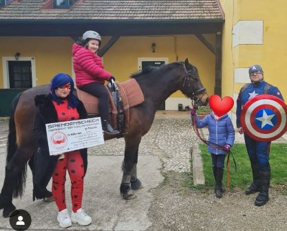 Ein kleines Mädchen reitet auf einem Pferd neben einem Marienkäfer und Captain America