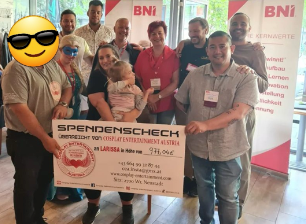 Eine Gruppe von Menschen hält einen großen Scheck mit der Aufschrift „Spendenscheck“ in der Hand.