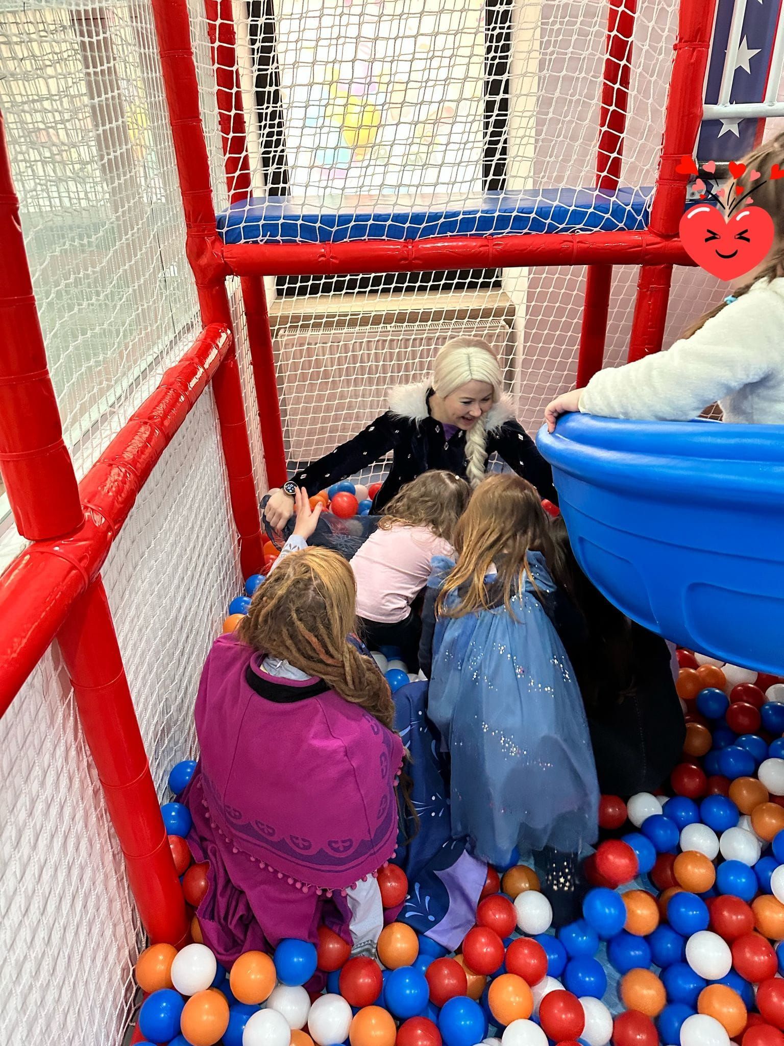 Eine Gruppe Kinder spielt in einem Bällebad mit einer Person verkleidet als Elsa.