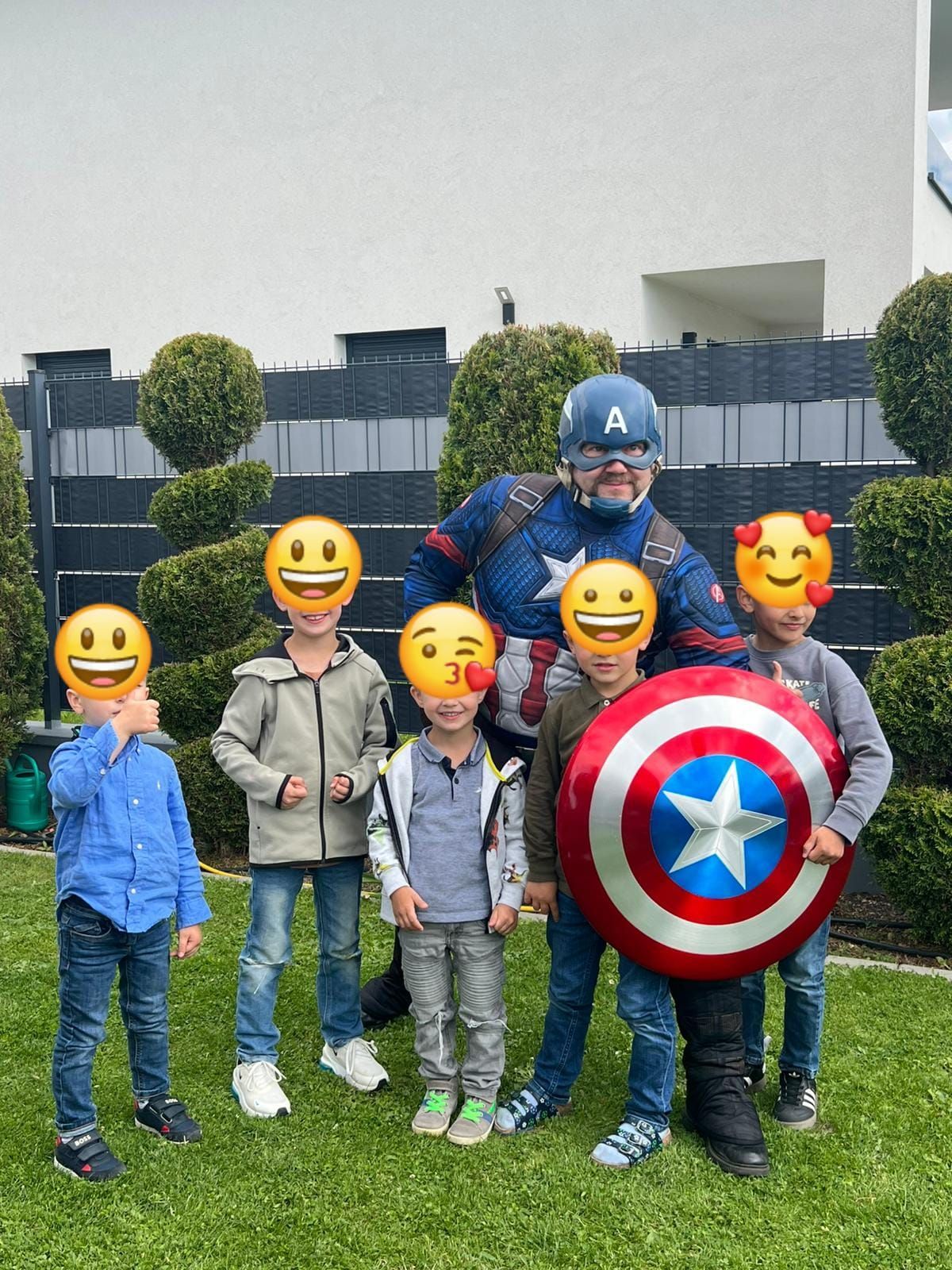Eine Gruppe Kinder posiert für ein Foto mit einem als Captain America verkleideten Mann.
