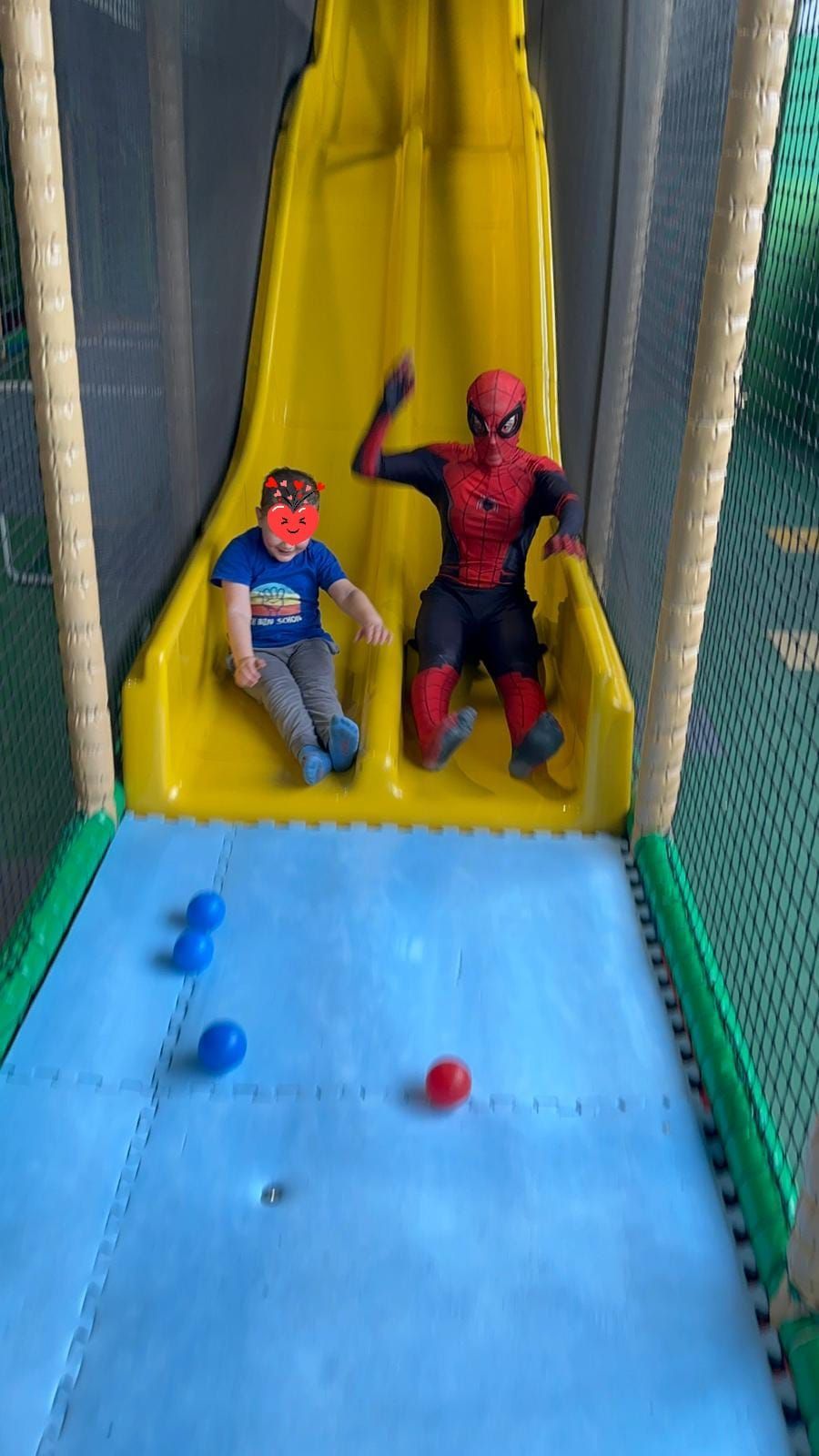 Zwei Kinder in Spiderman-Kostümen spielen auf einer Rutsche.