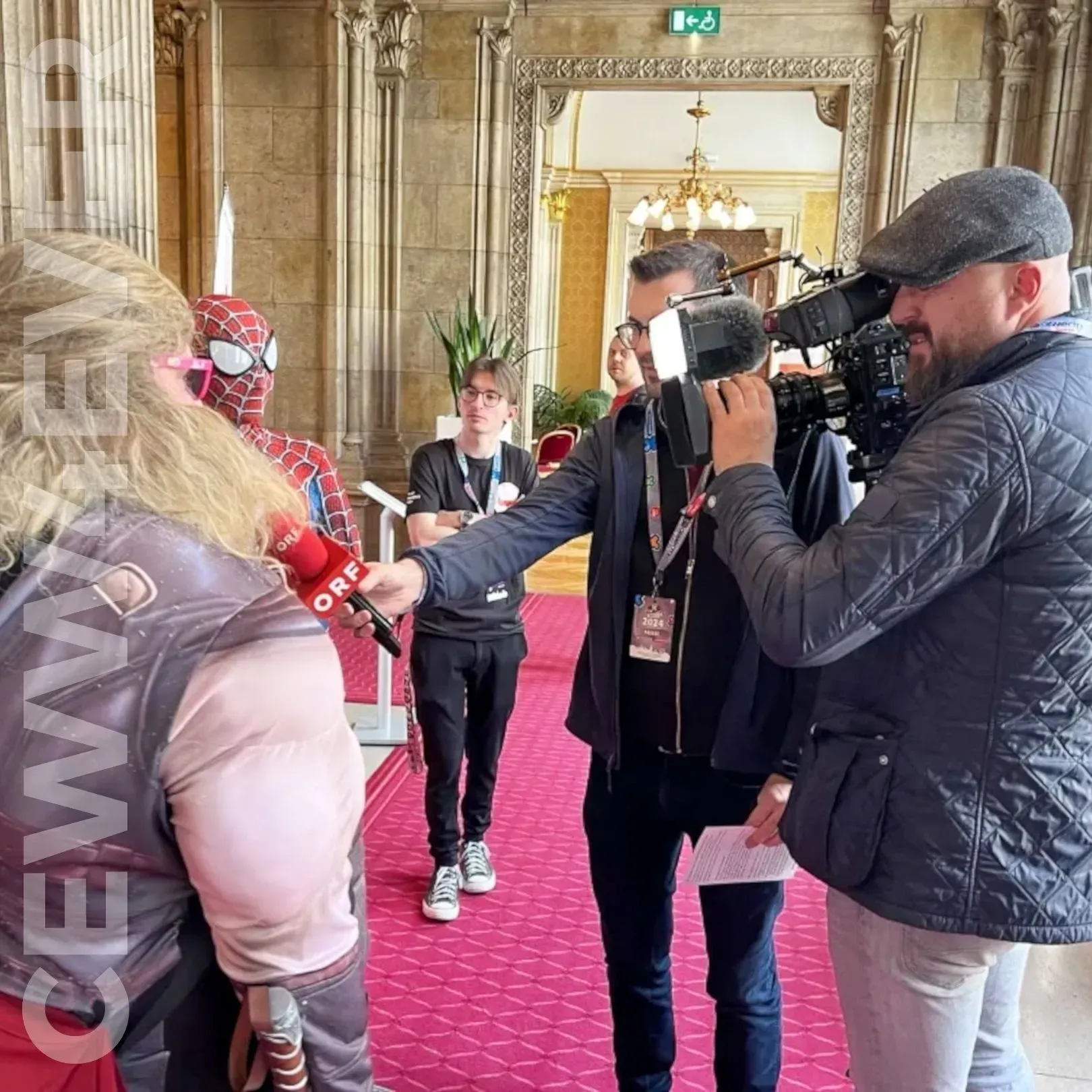 Ein Mann in einem Spiderman-Kostüm wird von einem Kameramann interviewt.