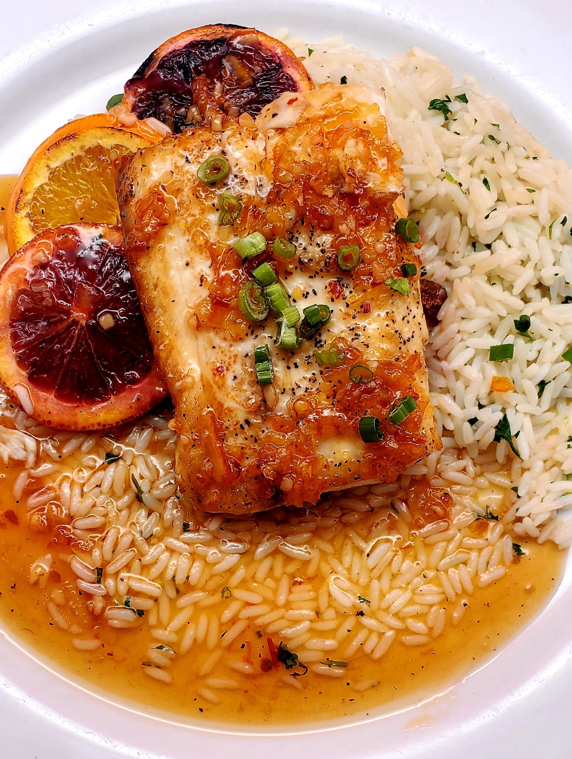 A white plate topped with rice and a piece of salmon.
