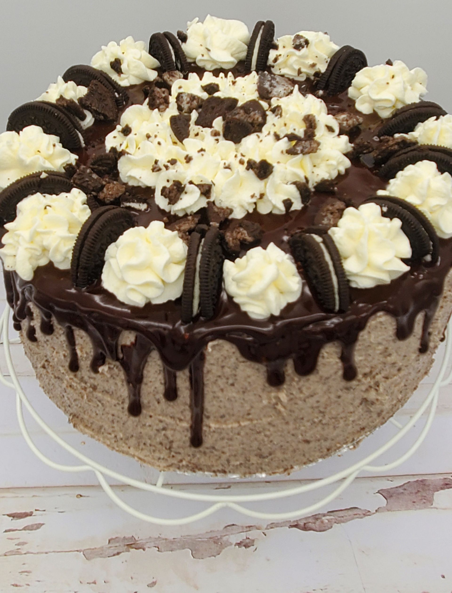 A chocolate cake with oreos and whipped cream on top