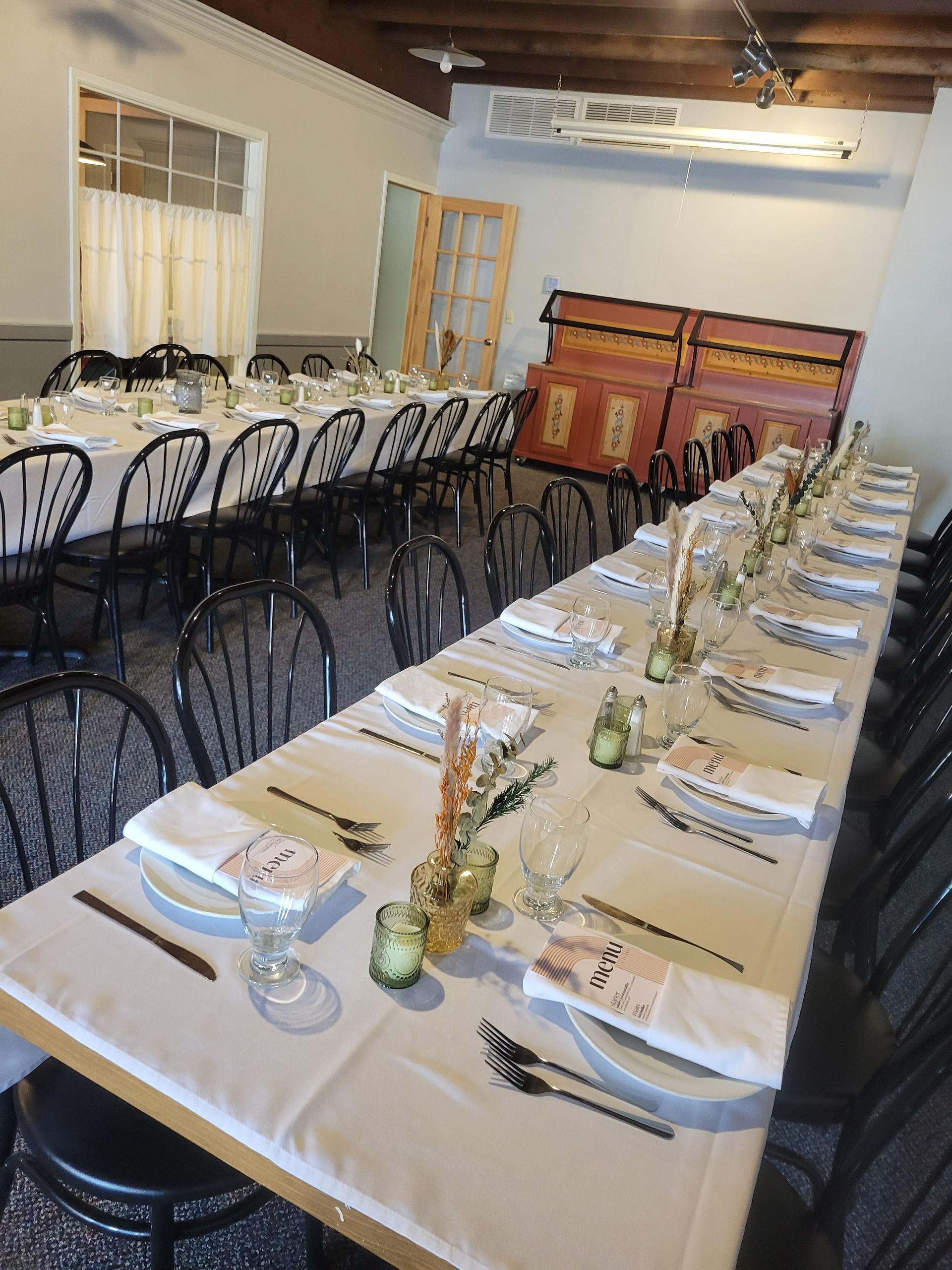 A long table with plates , napkins , utensils and candles on it