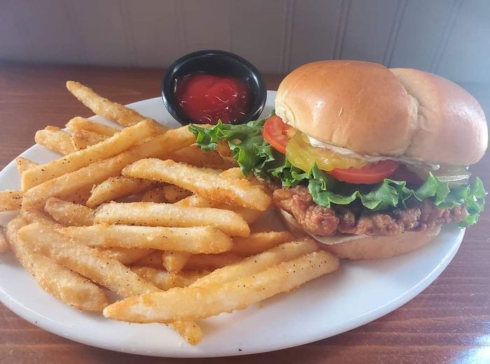 A chicken sandwich and french fries on a white plate.