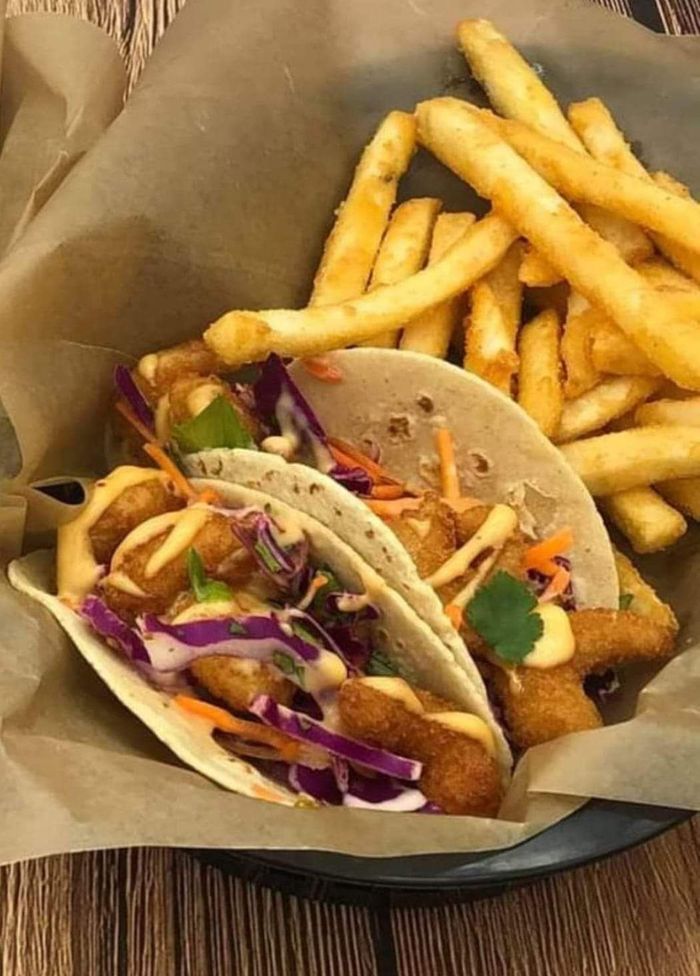 A bowl of tacos and french fries on a table.