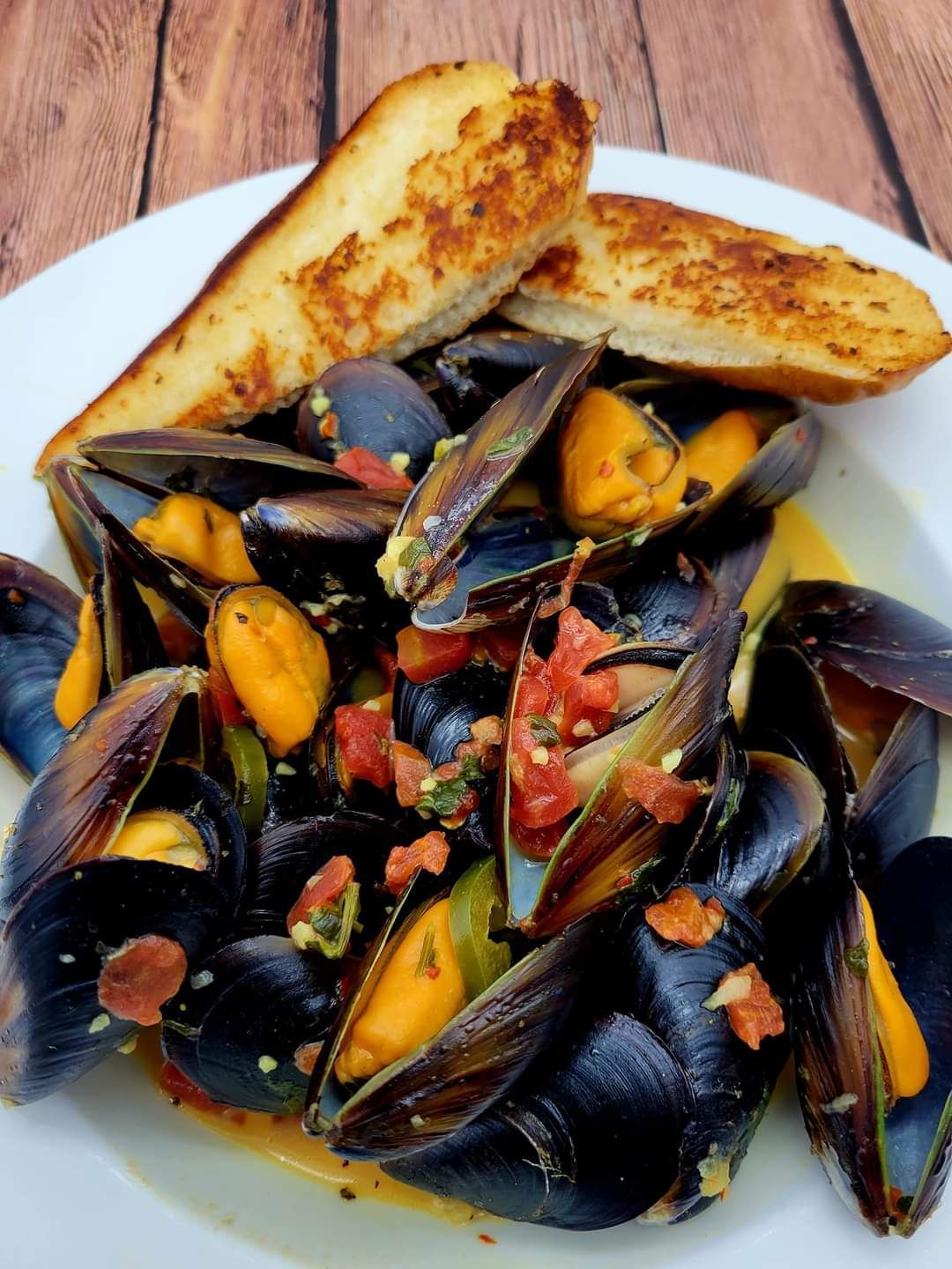 A white plate topped with mussels and garlic bread