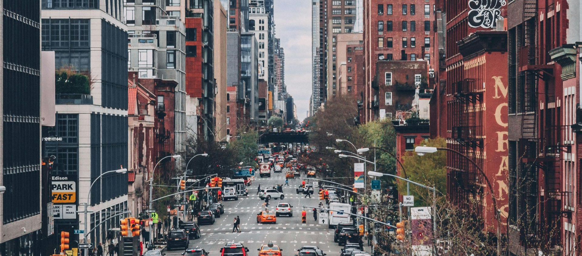 Busy city street with heavy traffic between tall buildings and colorful storefronts
